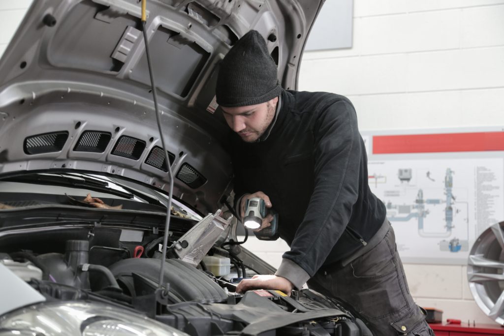 Mechanic looks under the hood of a car